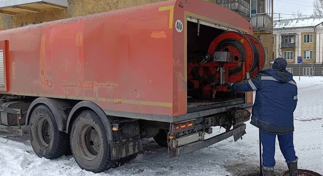 Каналопромывочная машина и работник прочищают засор в канализационной системе в Суворове